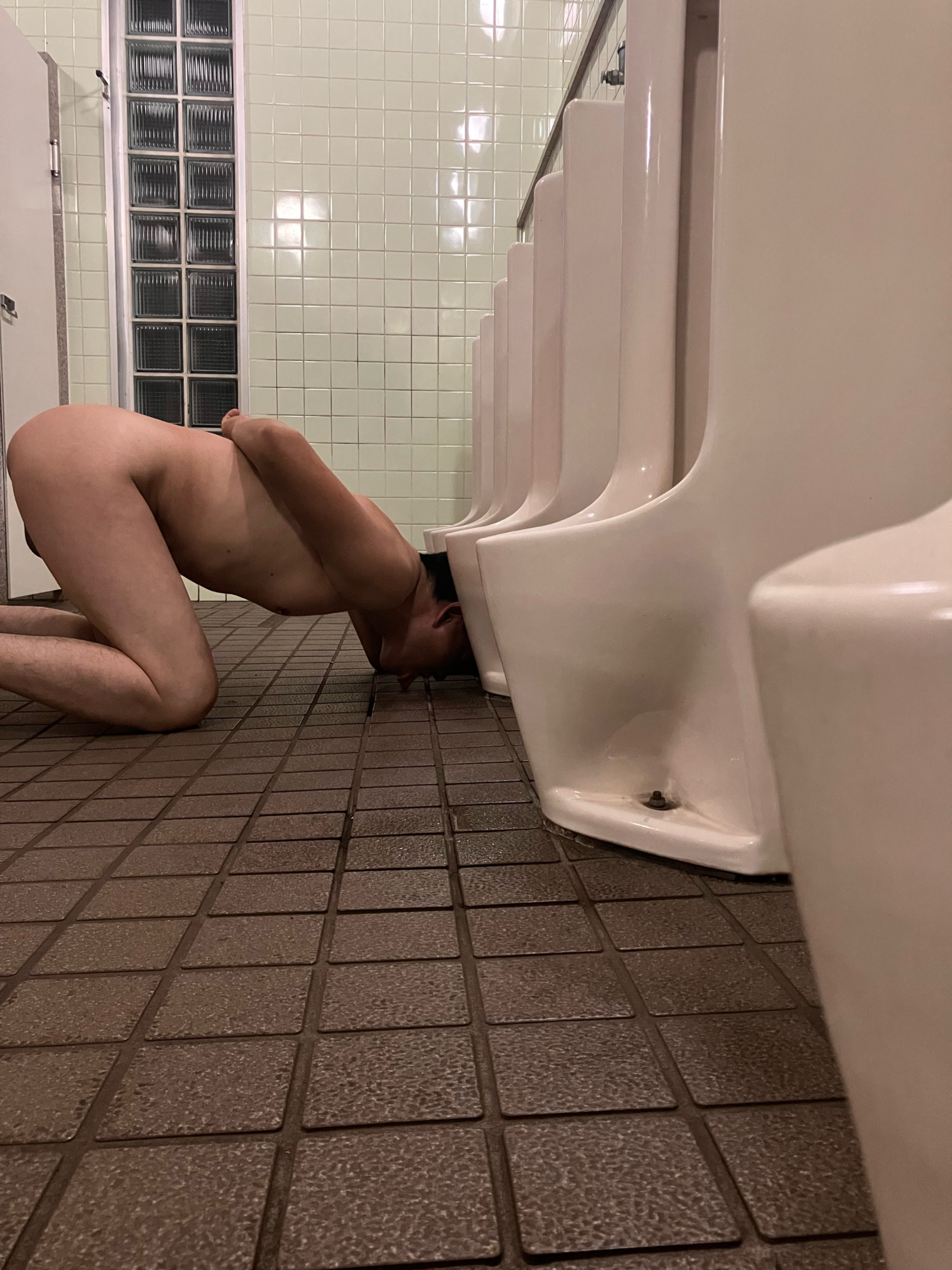 Humiliatingly licking the floor of a public restroom.